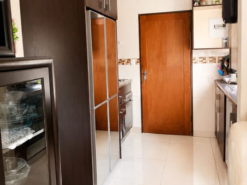 A functional kitchen featuring dark wood cabinetry, tiled flooring, and a tiled backsplash, providing a clean and practical workspace.