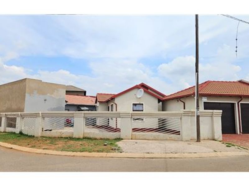 Front view of a residential property featuring a perimeter wall, tiled roof, and double garage with paved driveway access.