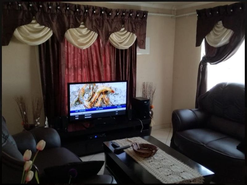 A living room area featuring tiled flooring and window treatments.