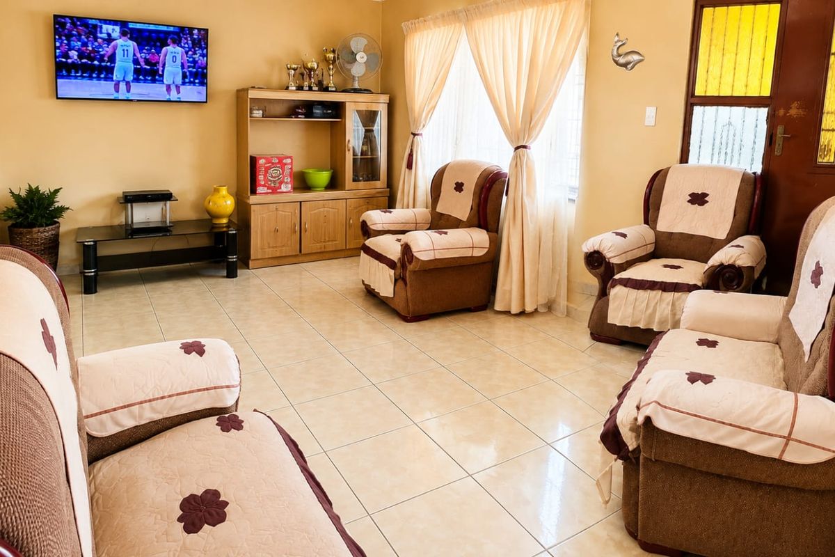 A comfortable living room featuring neutral tiled flooring and natural light through window curtains.