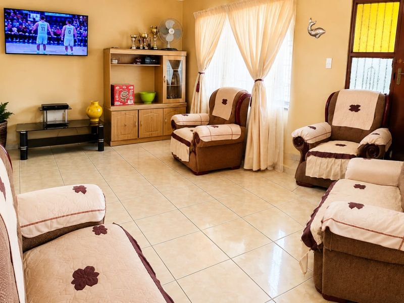 A comfortable living room featuring neutral tiled flooring and natural light through window curtains.