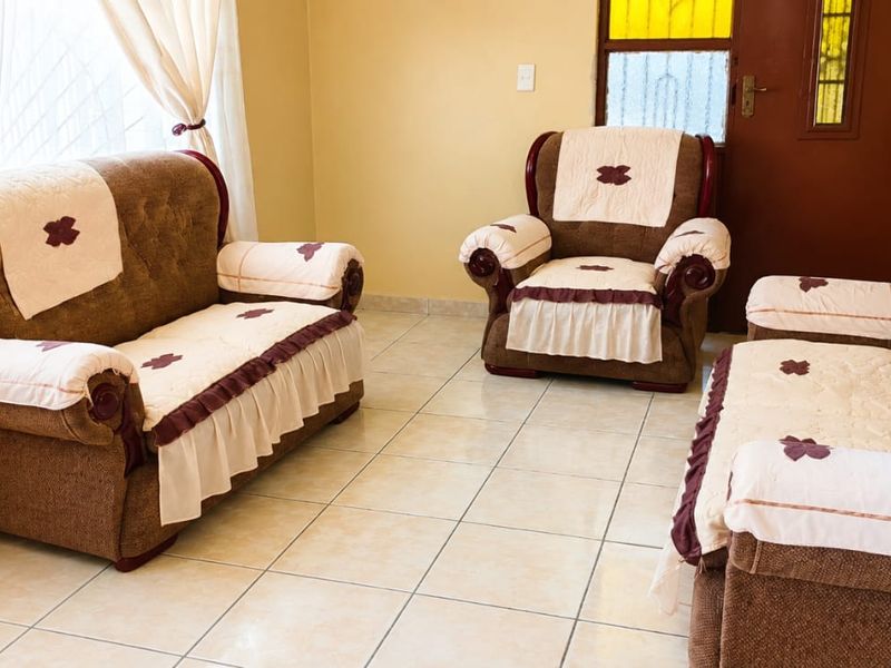 A living room area featuring neutral tiled flooring and a wooden door with a decorative stained glass insert.