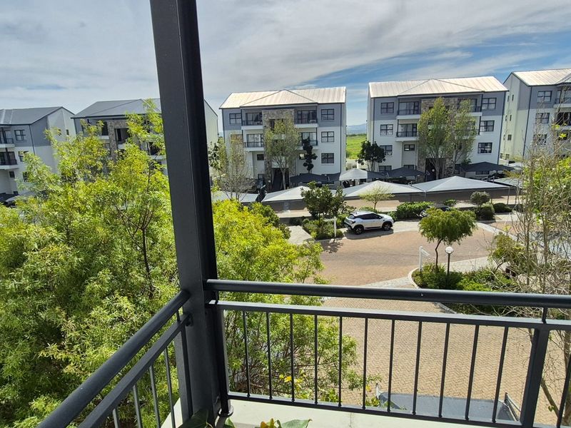 A view from a balcony overlooking a residential apartment complex with paved driveways and covered parking areas.