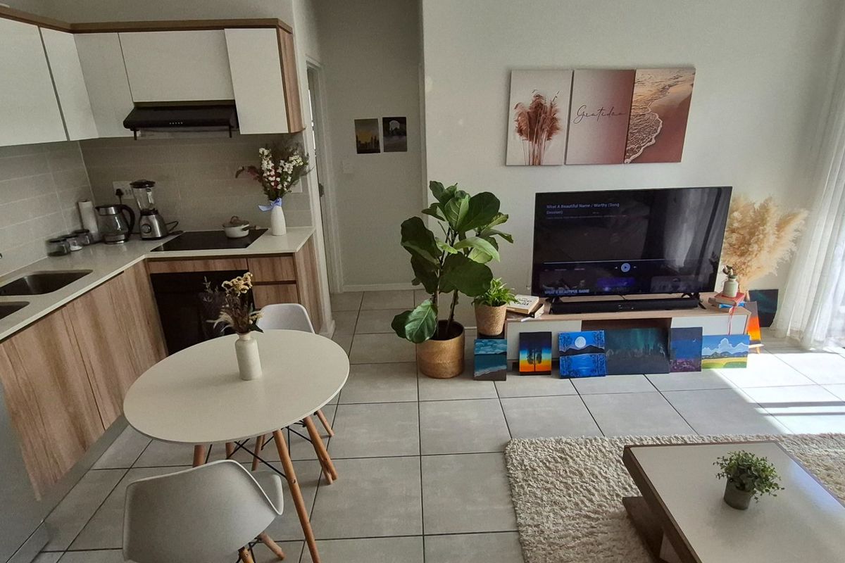 Modern open-plan apartment featuring a contemporary kitchen with stone countertops, integrated appliances, and seamless flow to a bright living area with balcony access.