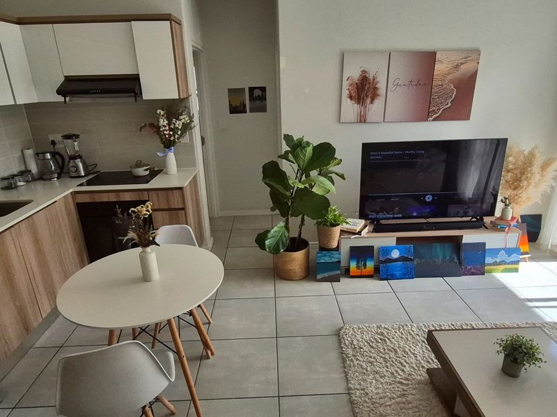 Modern open-plan apartment featuring a contemporary kitchen with stone countertops, integrated appliances, and seamless flow to a bright living area with balcony access.