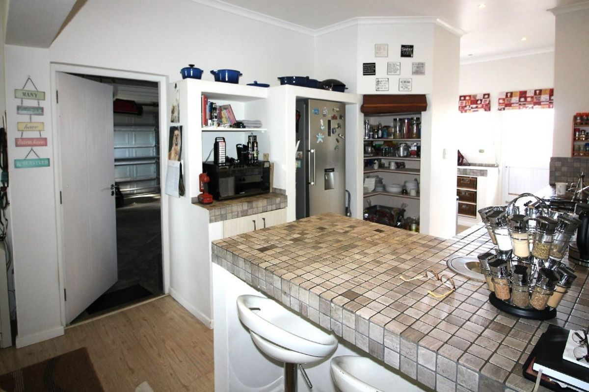 A functional kitchen featuring a tiled island, built-in pantry storage, and recessed shelving, offering a practical layout with potential for modern updates.
