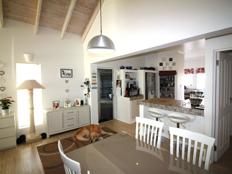 Open-plan living and kitchen area featuring a vaulted ceiling with exposed timber beams, a tiled breakfast bar, and integrated cabinetry.