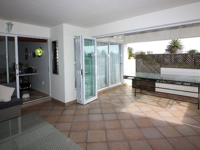 A spacious covered patio featuring tiled flooring, bi-fold doors, and sliding glass doors that provide seamless access to the outdoor area.
