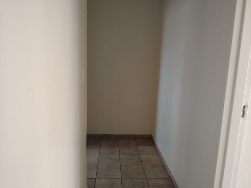 A simple, empty hallway featuring neutral wall finishes and tiled flooring, providing a clean transition space within the townhouse.