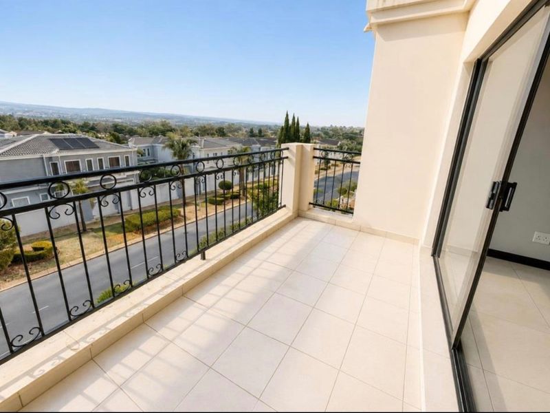 A clean, tiled balcony featuring a decorative wrought iron balustrade and sliding glass door access, offering elevated views of the surrounding residential area.
