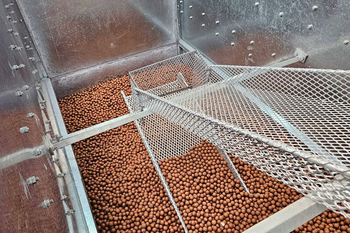 Industrial agricultural processing equipment featuring a galvanized steel hopper and integrated metal mesh sorting screen for farm produce handling.