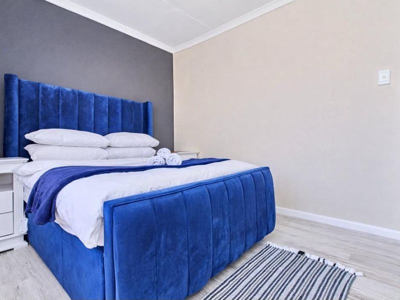 A well-maintained bedroom featuring light laminate flooring, a neutral color palette, and a dark grey accent wall.