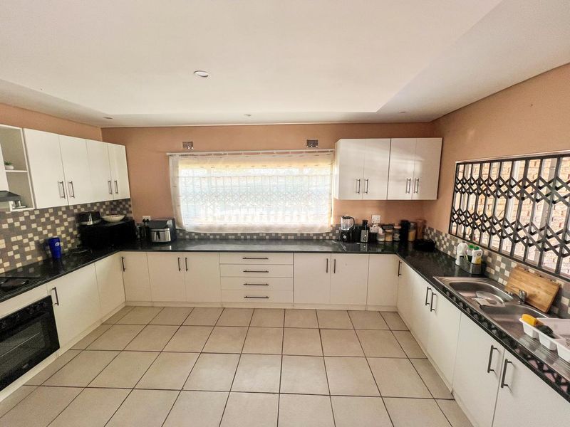 A functional kitchen featuring white cabinetry, dark granite countertops, tiled flooring, and a built-in oven, offering a clean and practical workspace.
