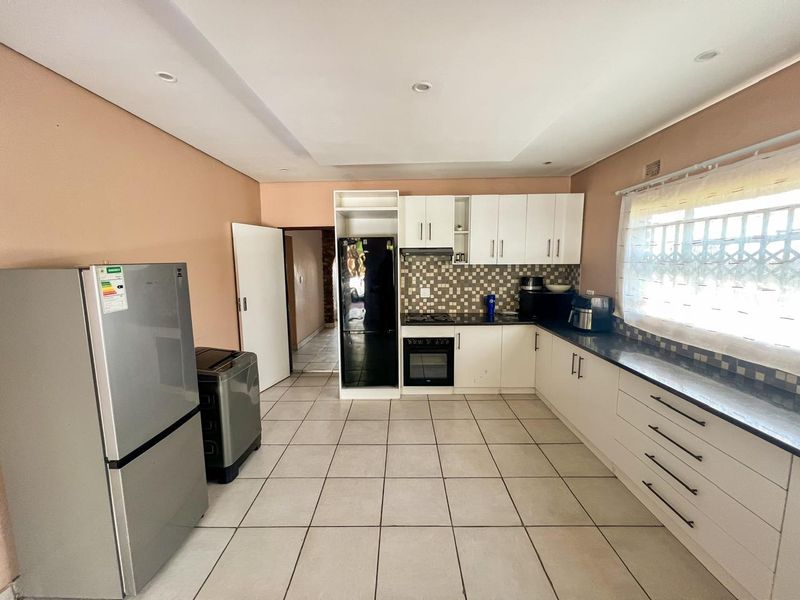 Functional kitchen featuring white cabinetry, granite countertops, built-in oven, gas hob, and tiled flooring with recessed lighting.