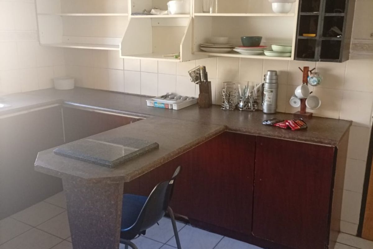 A functional kitchen featuring laminate countertops, built-in cabinetry with open shelving, and tiled flooring, offering potential for a modern renovation.