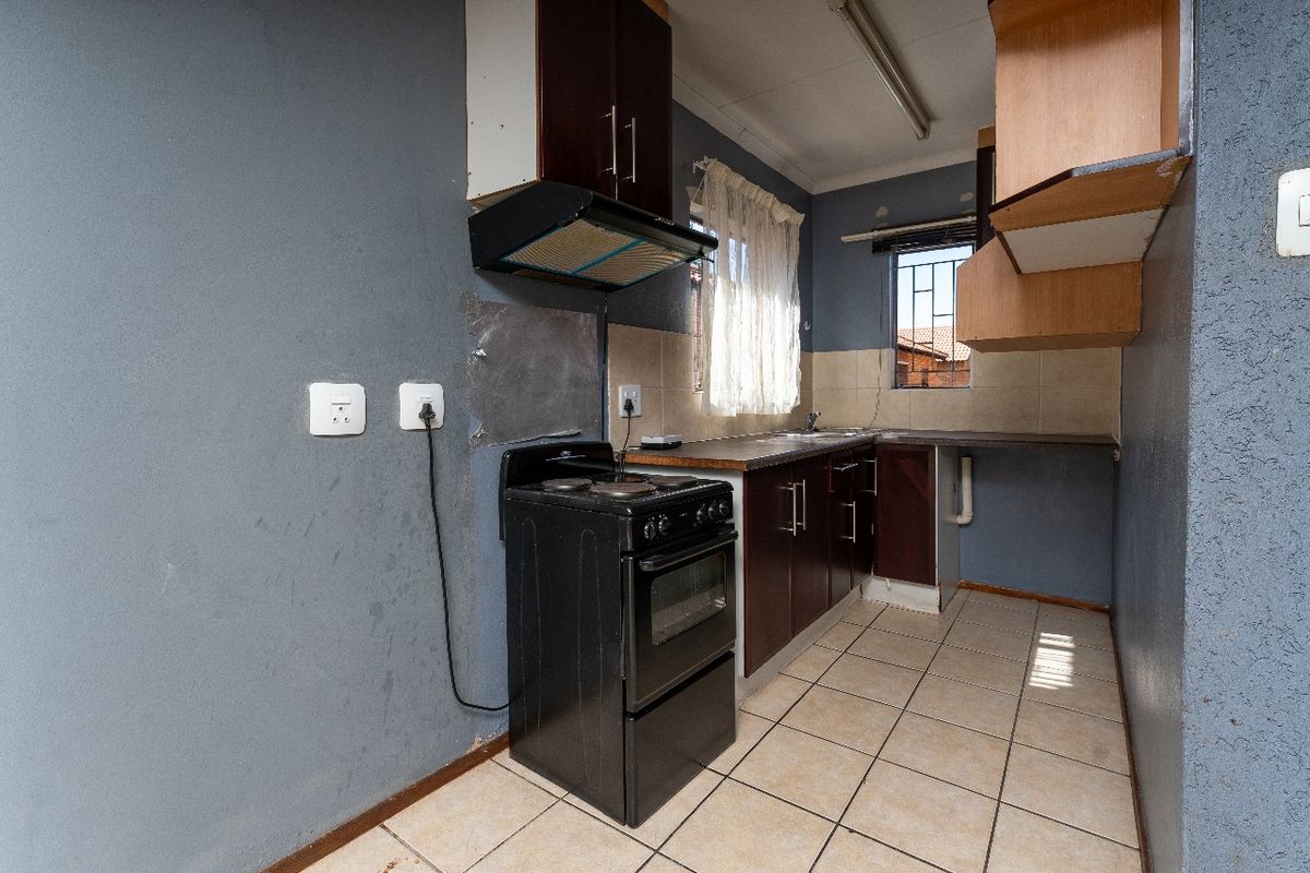 A functional kitchen featuring tiled flooring, built-in cabinetry, and a tiled splashback, requiring cosmetic updates to improve its overall condition and aesthetic appeal.
