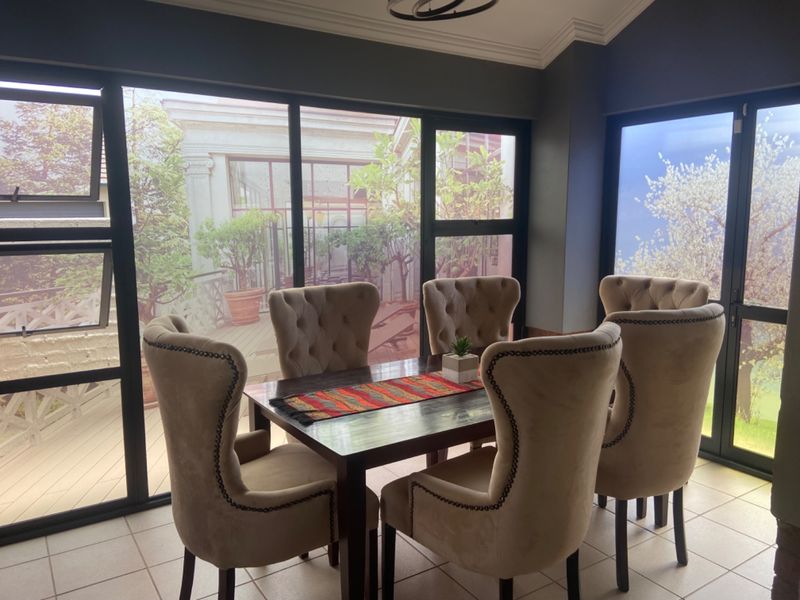 A bright dining area featuring large aluminium-framed windows that provide ample natural light and views of the outdoor space.