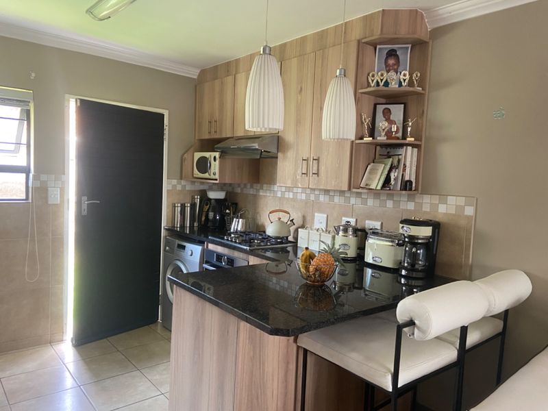 A functional kitchen featuring wood-finish cabinetry, granite countertops, a gas hob, and an integrated oven, with a breakfast nook and tiled flooring.