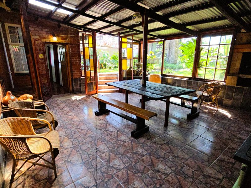 Covered outdoor patio area featuring tiled flooring, exposed beam ceiling, and a built-in braai, providing a functional space for outdoor entertaining.