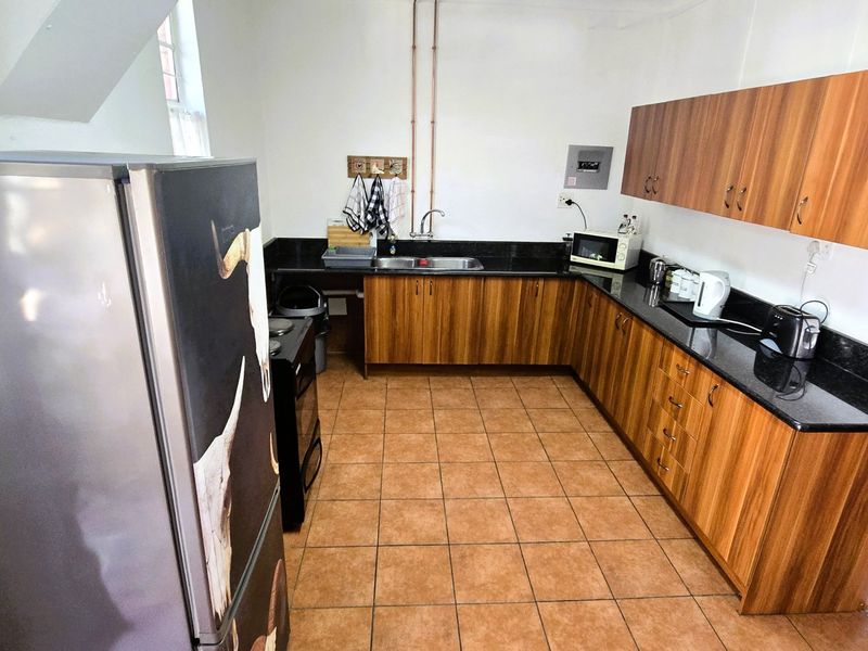 Functional kitchen featuring wood-look laminate cabinetry, granite countertops, ceramic floor tiles, and exposed copper plumbing fixtures.