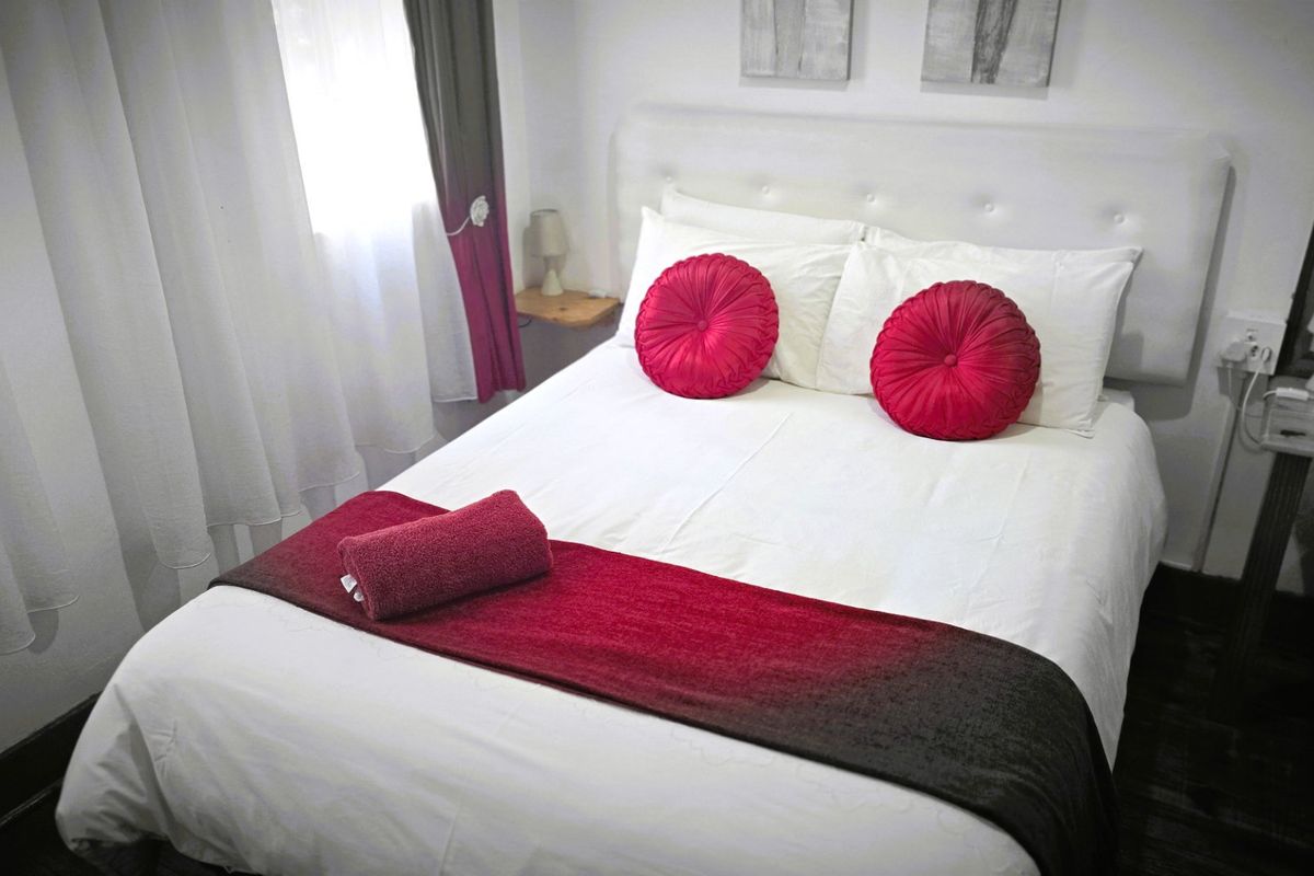 A compact bedroom featuring neutral walls and dark flooring, providing a functional sleeping space.