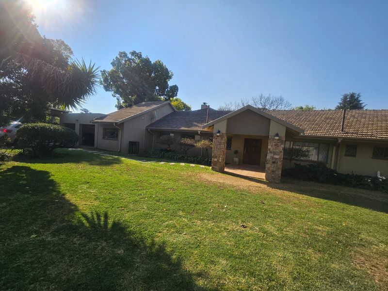 Front elevation of a single-story house featuring a tiled roof, stone-clad entrance pillars, a covered porch, and an attached double garage set in a garden.