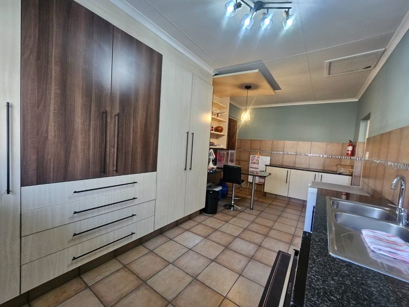 Spacious kitchen featuring extensive built-in cabinetry, granite countertops, double basin sink, and a dedicated built-in desk area with tiled flooring throughout.
