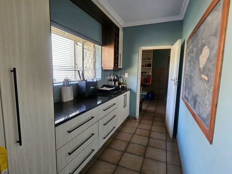 A functional scullery featuring granite countertops, ample built-in cabinetry, a wine rack, and tiled flooring, providing additional prep and storage space.