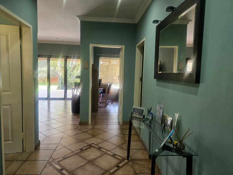 A spacious hallway featuring tiled flooring, decorative cornice, and recessed lighting, providing access to adjacent living areas and an office space.