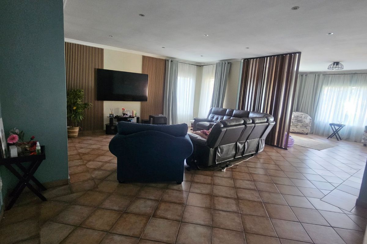 Spacious living area featuring large format floor tiles, recessed downlighting, and a decorative slatted timber feature wall with integrated television mounting.