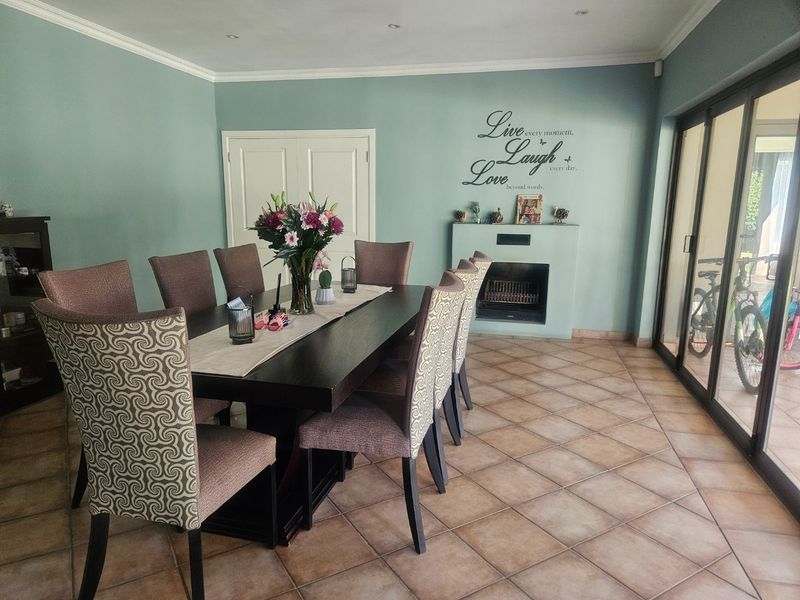 A spacious dining room featuring tiled flooring, a built-in fireplace, and large sliding glass doors that provide ample natural light and outdoor access.