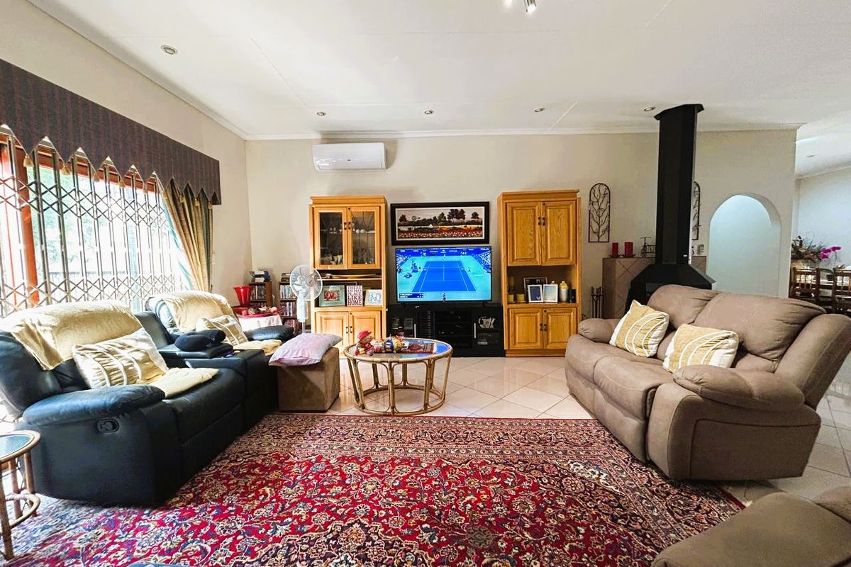 Spacious living room featuring tiled flooring, a built-in fireplace, and a wall-mounted air conditioning unit, offering a comfortable and functional family space.