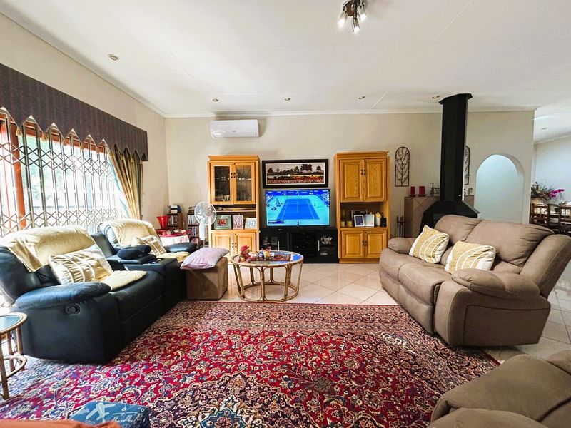 Spacious living room featuring tiled flooring, a built-in fireplace, and a wall-mounted air conditioning unit, offering a comfortable and functional family space.
