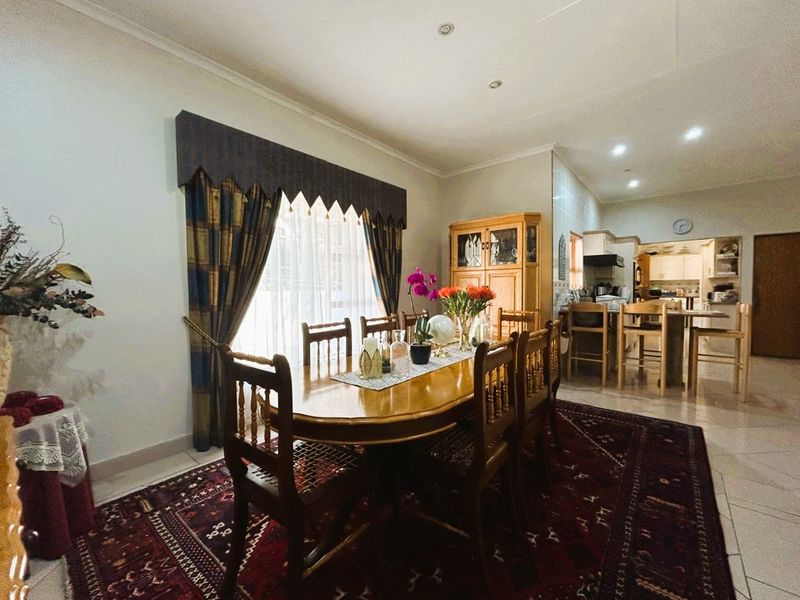 Open-plan dining area flowing into a functional kitchen with tiled flooring and recessed lighting.