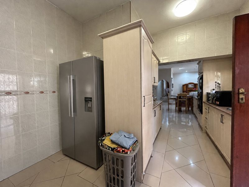 A functional kitchen featuring tiled walls, tiled flooring, and built-in cabinetry with laminate countertops, providing a practical layout with an open flow to adjacent rooms.
