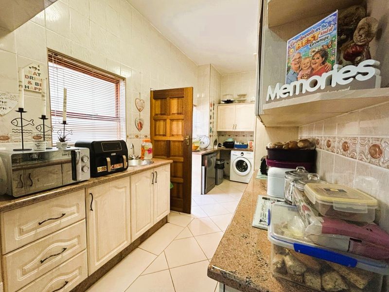 Functional kitchen featuring built-in cabinetry, granite countertops, and tiled finishes, with an integrated laundry area and direct access to the rest of the home.