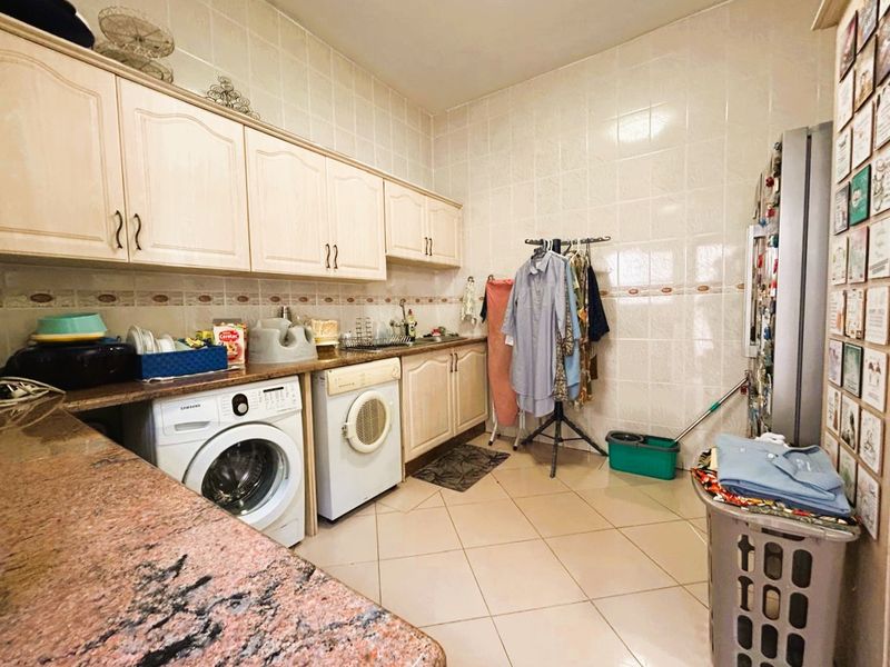 Functional laundry room featuring built-in cabinetry, granite countertops, and tiled finishes, providing dedicated space for washing appliances and utility tasks.