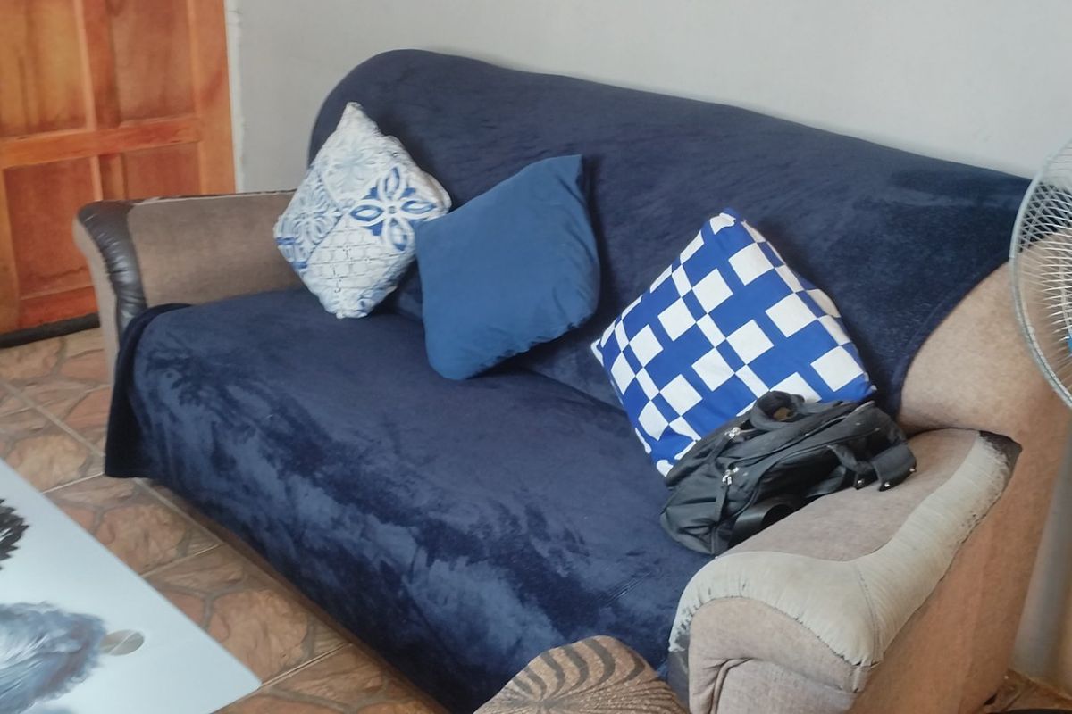 A living room area featuring tiled flooring and a wooden door, providing a functional space for relaxation.