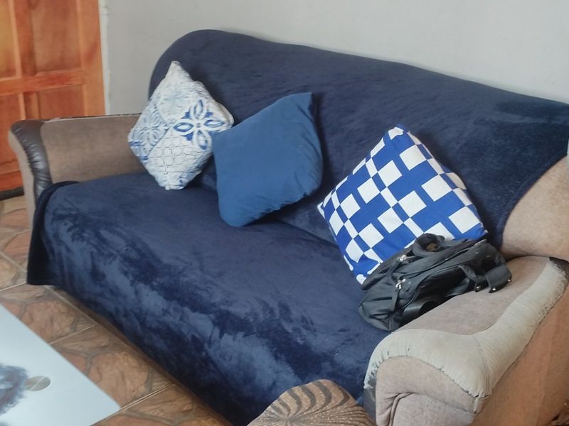 A living room area featuring tiled flooring and a wooden door, providing a functional space for relaxation.