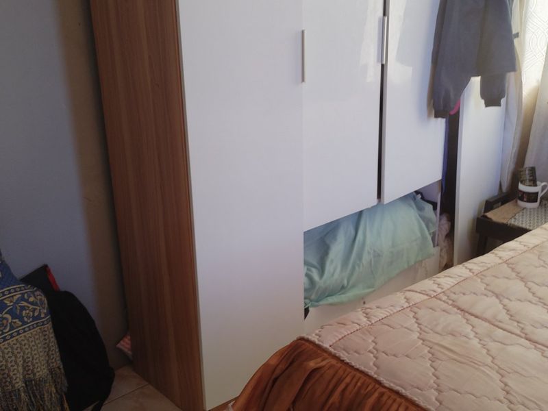 A bedroom featuring a modern built-in wardrobe with white and wood-grain finish doors.