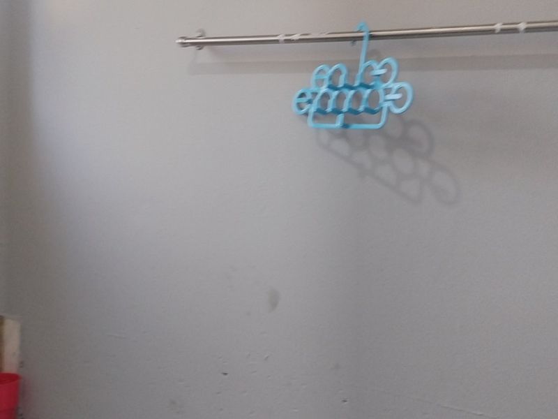 A functional laundry area featuring a wall-mounted rail and tiled splashback, currently presenting as a basic utility space in need of minor cosmetic updates.