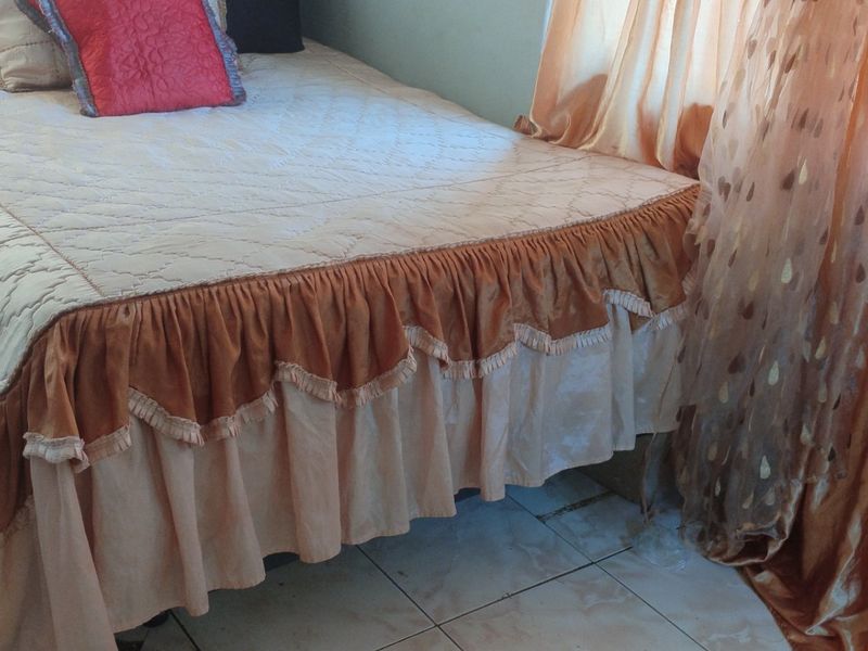 A bedroom featuring tiled flooring and natural light through window curtains.
