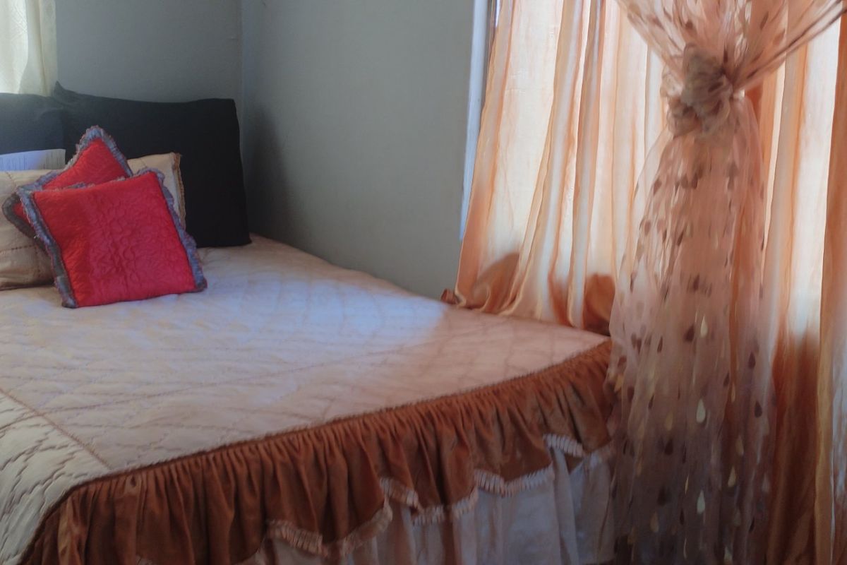 A bedroom featuring natural light through window curtains.