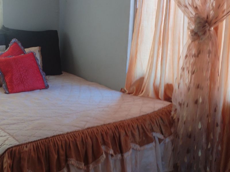 A bedroom featuring natural light through window curtains.