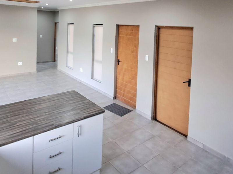 Spacious open-plan living area featuring tiled flooring, recessed lighting, and a modern kitchen island with a laminate countertop.
