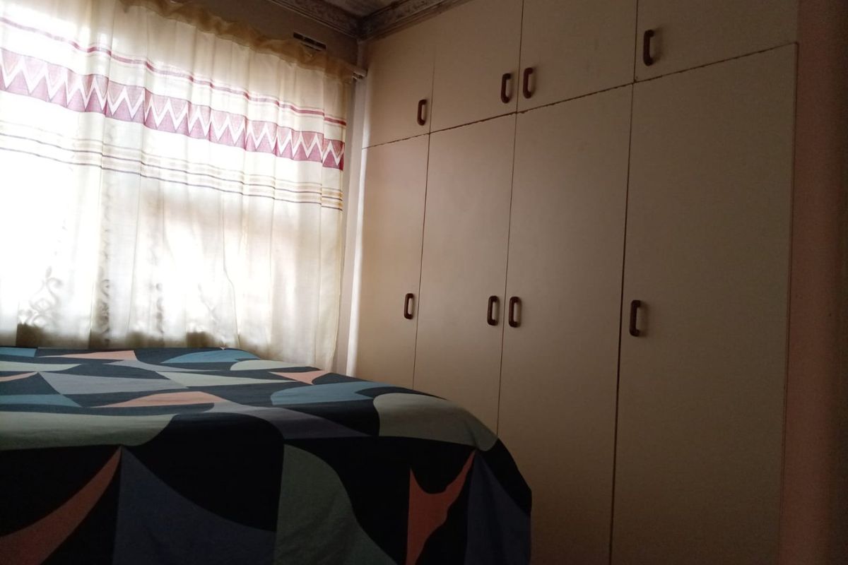 Bedroom featuring built-in cupboards and ceiling cornice, showing signs of water damage on the ceiling.