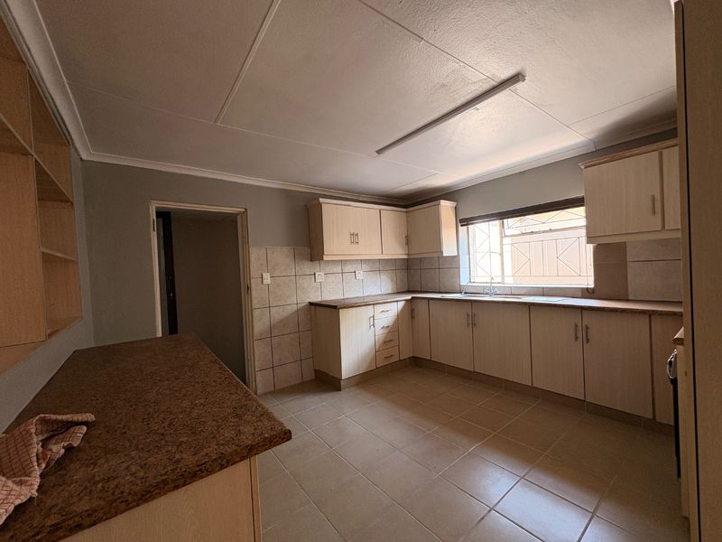 A functional kitchen featuring built-in cabinetry, laminate countertops, tiled backsplash, and tiled flooring, offering a clean and practical space for culinary activities.
