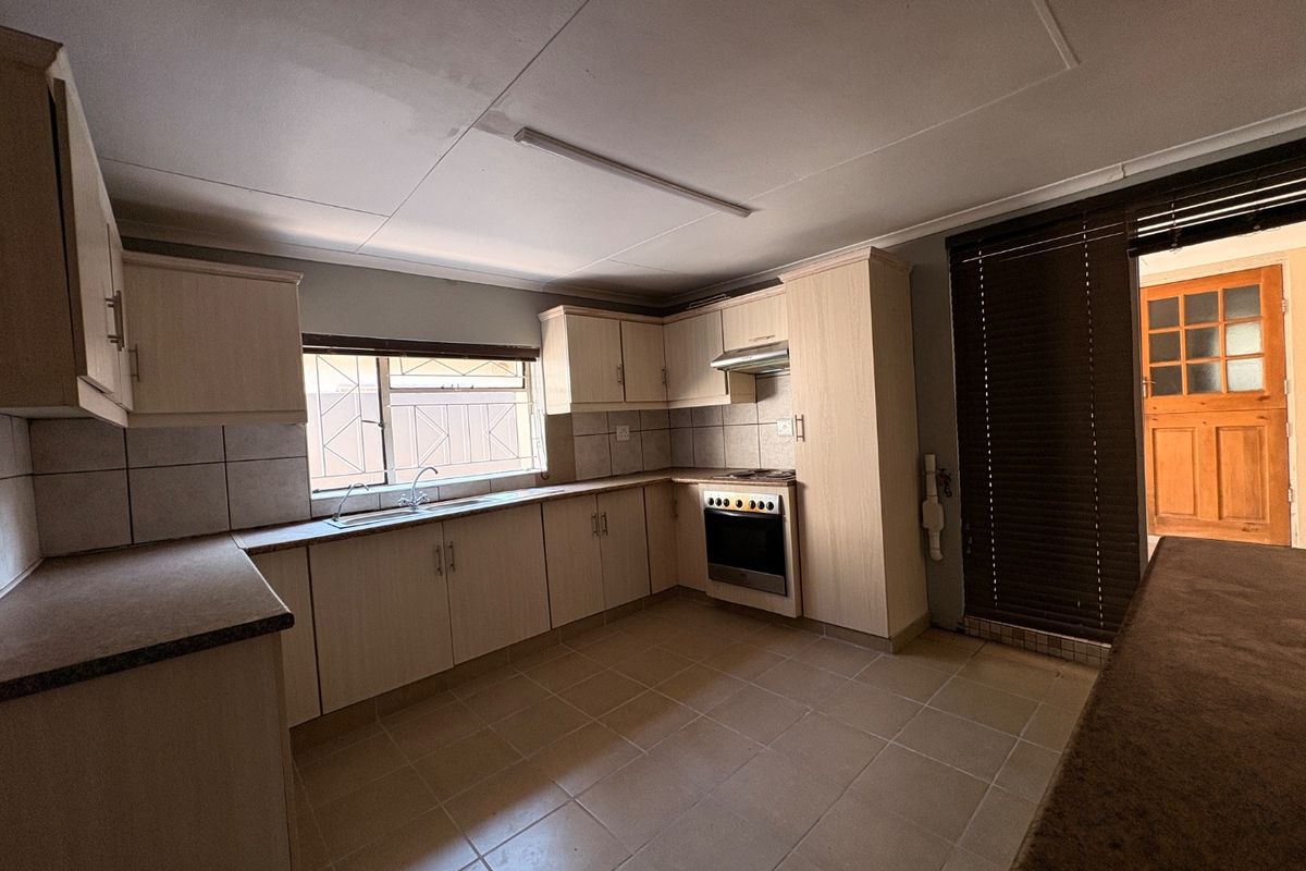 A functional kitchen featuring built-in cabinetry, laminate countertops, a built-in oven with extractor fan, and tiled flooring, offering a clean and practical workspace.