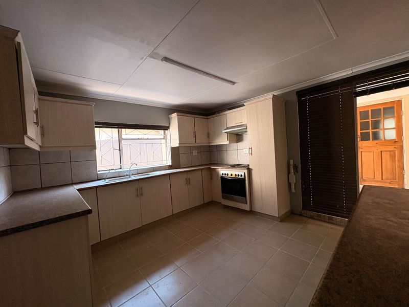 A functional kitchen featuring built-in cabinetry, laminate countertops, a built-in oven with extractor fan, and tiled flooring, offering a clean and practical workspace.