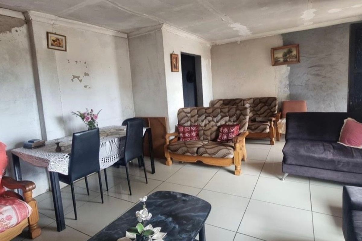 A living room area featuring ceramic floor tiles and coved ceilings, currently requiring significant cosmetic updates to the wall and ceiling finishes.